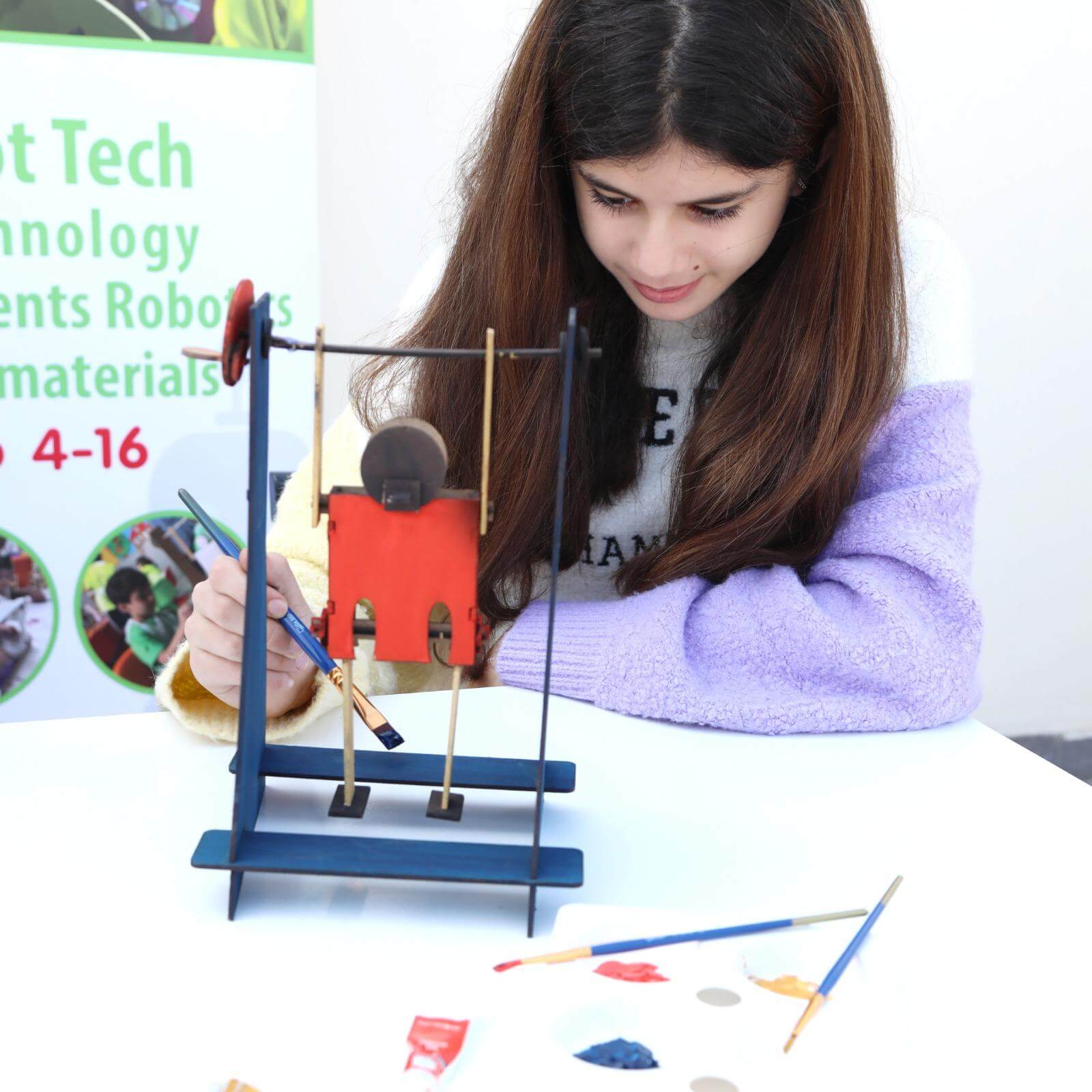 A girl happily painting her Acrobat kit after building it herself